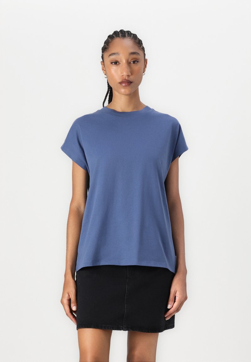 Blaues Baumwoll-T-Shirt mit kurzen Ärmeln und rundem Ausschnitt, kombiniert mit einem schwarzen Jeansrock. Schlichtes, lockeres Design.