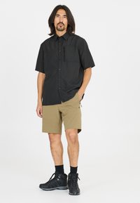 Zwarte kortemouwen overhemd met knopen en een borstzak, gecombineerd met kaki shorts en zwarte wandelschoenen. Glad stof, functioneel ontwerp.