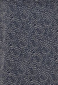 Tessuto blu navy con un motivo floreale bianco ripetuto, caratterizzato da petali allungati disposti in un design radiante, texture liscia.
