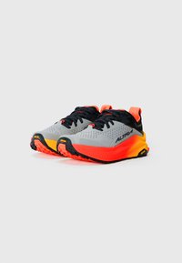 Chaussures de sport grises et noires avec des accents rouges et oranges, dotées d'une tige texturée, d'une semelle extérieure épaisse et d'un profil de semelle prononcé pour une meilleure adhérence.