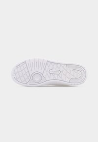 Άσπρη σόλα παπουτσιού με ανάγλυφα υφασμένα σχέδια, κυκλικό μοτίβο κοντά στην περιοχή της μπάλλας και το όνομα της μάρκας «LACOSTE» ανάγλυφο στο κέντρο.