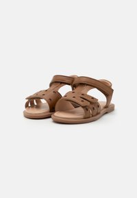 Braune Kunstleder-Sandalen mit offenem Zehenbereich, verstellbaren Riemen und einem Sterne-Muster auf dem Obermaterial. Flache Sohle.