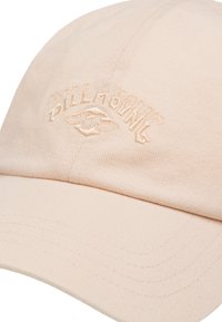Peach corduroy cap featuring embroidered "BILLABONG" logo and curved visor. Textured fabric with visible stitching and slight sheen.