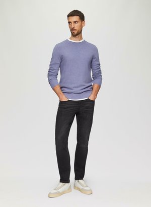 Pull en laine texturé de couleur violet clair avec un col blanc, associé à un jean slim noir et des baskets blanches avec des accents beiges.