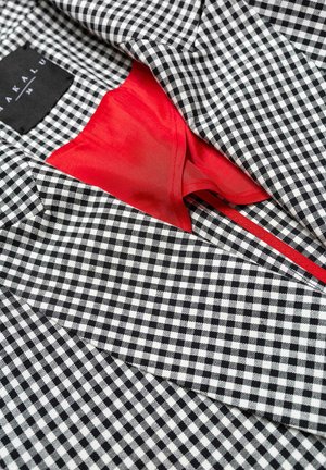 Czarnobiała tkanina w kratkę typu gingham z czerwoną podszewką. Posiada dopasowany krój oraz widoczne detale szwów. Zawiera metkę marki.