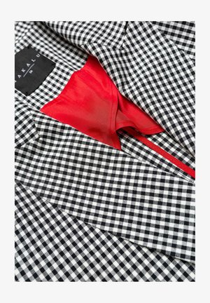 Czarnobiała tkanina w kratkę typu gingham z czerwoną podszewką. Posiada dopasowany krój oraz widoczne detale szwów. Zawiera metkę marki.