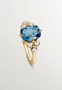Anillo de oro con una gran gema rectangular azul, adornado con tres diamantes redondos más pequeños, con un diseño de banda pulida y suave.