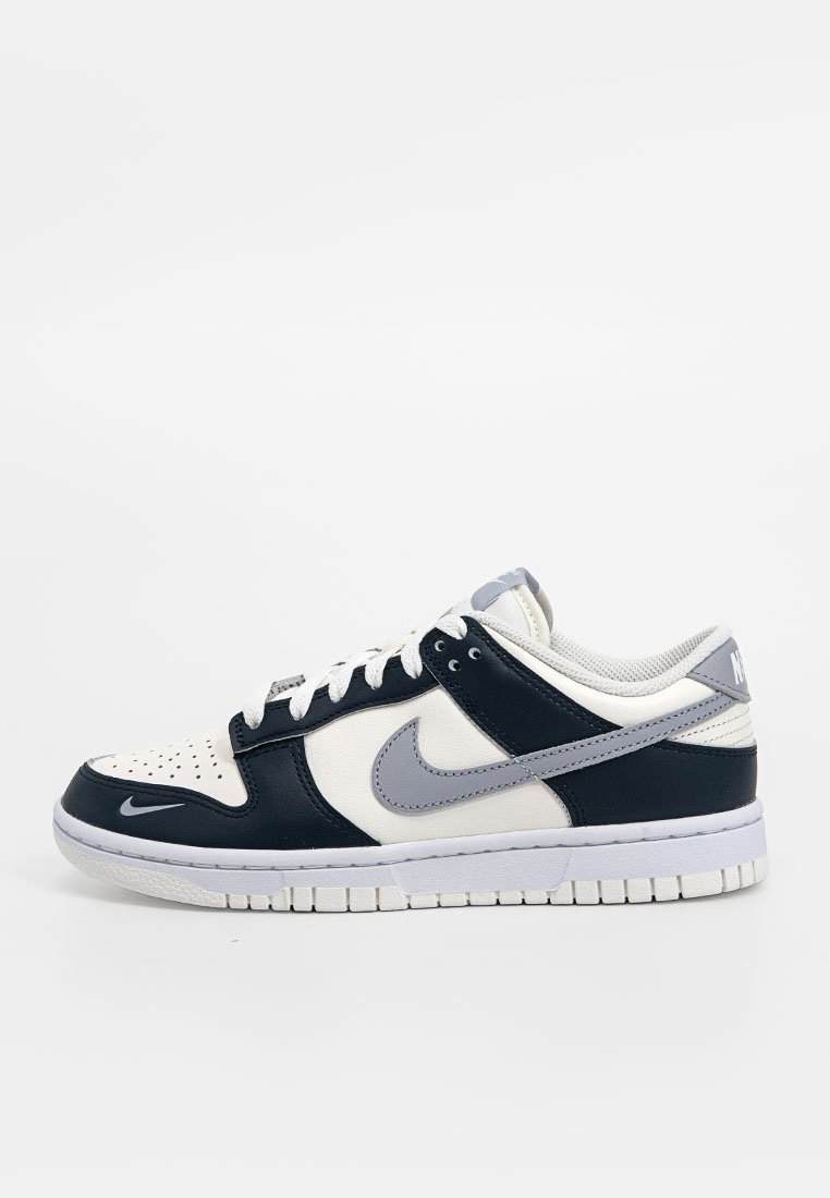 Le sneakers Nike presentano una tomaia in pelle blu navy e bianca, accenti grigi, una punta perforata e una suola in gomma bianca con battistrada testurizzato.