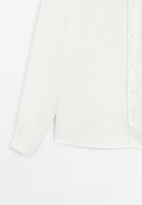 Weißes Langarmhemd mit Knopfverschluss, aus leichtem Stoff gefertigt. Verfügt über einen abgerundeten Saum und detaillierte Manschetten, glatte Textur.