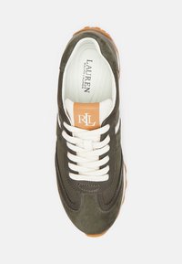 Gröna mockaskor med vita detaljer och snören, med en brun logotypbricka på tungan. Gummisula med strukturerat grepp.