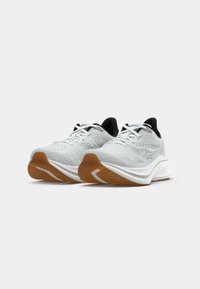 Pair of white and gray mesh running shoes with brown rubber soles and black interior lining on a white background.