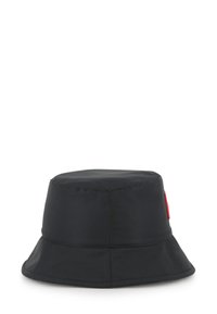 Un chapeau seau noir en tissu lisse avec un large bord et un accent logo rouge sur le côté. Forme cylindrique générale avec un sommet plat.