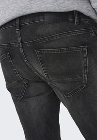 Zwarte denim jeans met een gestructureerde afwerking, versterkte stiksels en twee achterzakken. De tailleband heeft een leren merkpatch.
