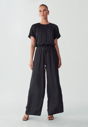 Zwarte jumpsuit met korte mouwen, een ronde halslijn, geplooide details, een elastische taille met een trekkoord en een wijde broekspijp.