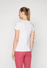 Camiseta blanca de manga corta, diseño ajustado, cuello redondo, hecha de material suave, combinada con leggings rosas. Textura suave, con detalles mínimos.