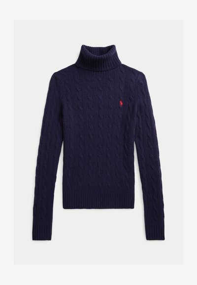 Marineblå kabelstrikket genser med høy hals, lange ermer og liten rød brodert logo på venstre bryst.