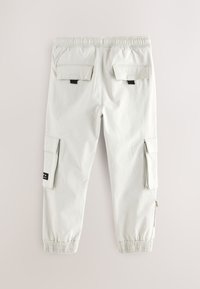 Pantaloni cargo grigio chiaro con vita e polsini elasticizzati, due tasche posteriori con patta e tasche cargo laterali con linguette nere per la chiusura.