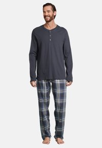 Pyjamas pour homme comprenant un haut à manches longues gris foncé avec un col henley et un pantalon de pyjama à carreaux dans des tons de bleu, gris et blanc.