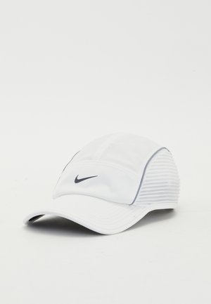 Casquette de sport blanche avec un devant structuré, un tissu doux et des panneaux latéraux texturés. Présente un logo Nike noir sur le devant.