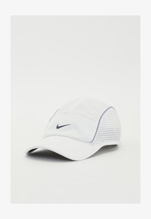 Biała czapka sportowa z usztywnionym przodem, miękkiego materiału i teksturowanymi bocznymi panelami. Z przodu widoczny czarny logotyp Nike.