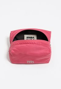 Pequeño pouch rosa claro con cremallera, mostrando un interior negro y una etiqueta blanca con el texto en negro "Bimba Y Lola". El nombre de la marca también en la parte frontal exterior.