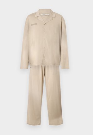 Ensemble de vêtements de détente beige en tissu doux, comprenant une chemise à manches longues avec boutons et un pantalon assorti à la coupe décontractée.