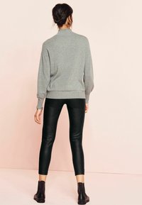 Maglione grigio con collo alto, abbinato a leggings neri in ecopelle. Design semplice, vestibilità standard, polsini e orlo a coste, lunghezza alla caviglia.