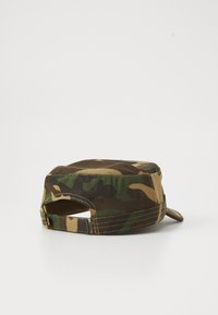 Gorra ajustable de patrón de camuflaje con la parte superior plana y visera pequeña, mostrada desde atrás sobre un fondo claro y liso.