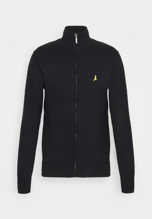 Sudadera negra con cremallera y cuello alto, con puños y dobladillo acanalados. Presenta un pequeño logo bordado amarillo en el lado izquierdo del pecho.