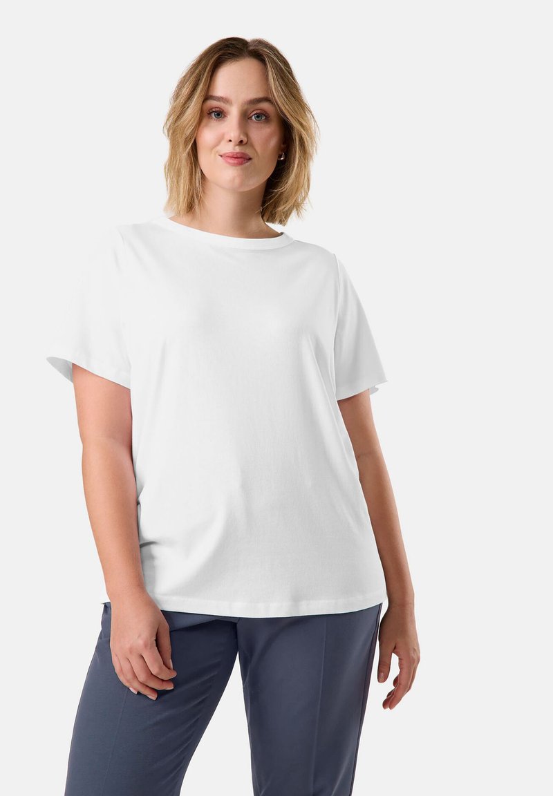 White short-sleeve T-shirt made from soft cotton, featuring a round neckline and a relaxed fit, paired with gray pants.