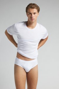 Biała bawełniana koszulka i slipy, dopasowany fason, gładka faktura, klasyczny okrągły dekolt i elastyczny pas. Model pozujący z rękami na biodrach.