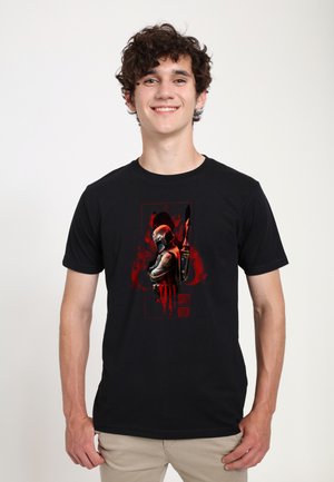 Camiseta de algodón negra con un gráfico de un personaje enmascarado con acentos rojos y efectos de salpicaduras. Diseño de manga corta y cuello redondo.