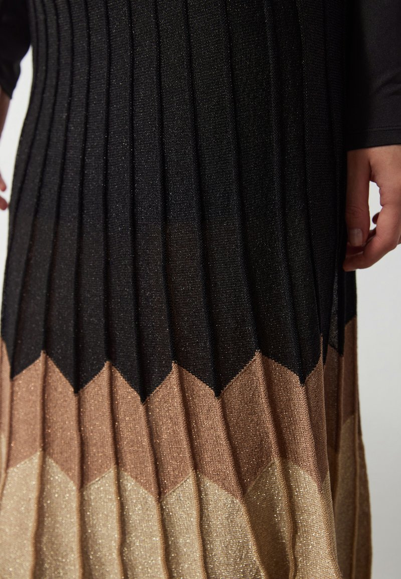 Schwarzer und metallischer Faltenrock mit Zickzack-Muster in Braun- und Goldtönen, mit einer strukturierten Oberfläche und schimmerndem Effekt.