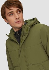 Groene gewatteerde jas met een rits- en klittenbandsluiting, voorzien van een capuchon, gewatteerde textuur en twee zijzakken.