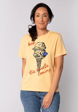 Gele katoenen T-shirt met een ijsbeker graphic en rode tekst die zegt "hou de zoetigheden maar komen." Casual fit met korte mouwen.