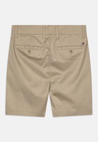 Béžové bavlněné šortky s hladkou texturou, včetně zapínání na knoflík, dvou zadních kapes a jemných švů.