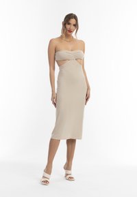 Abito midi beige senza spalline con un corpetto intrecciato e ritagli laterali. Realizzato in tessuto liscio, presenta una silhouette aderente e una leggera lucentezza.
