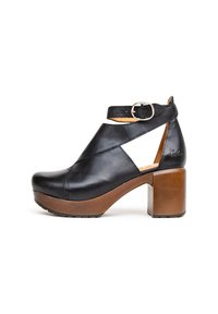 Zwarte leren platformhakken met een chunky bruine blokhak, voorzien van een band met een zilveren gesp en uitsnijdingen aan de zijkanten.