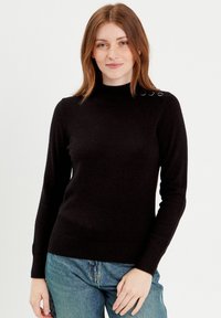 Sort strikpullover med høj hals og lange ærmer. Har dekorative knapper på skulderen og en tætsiddende talje. Materiale i bomuldsblanding.