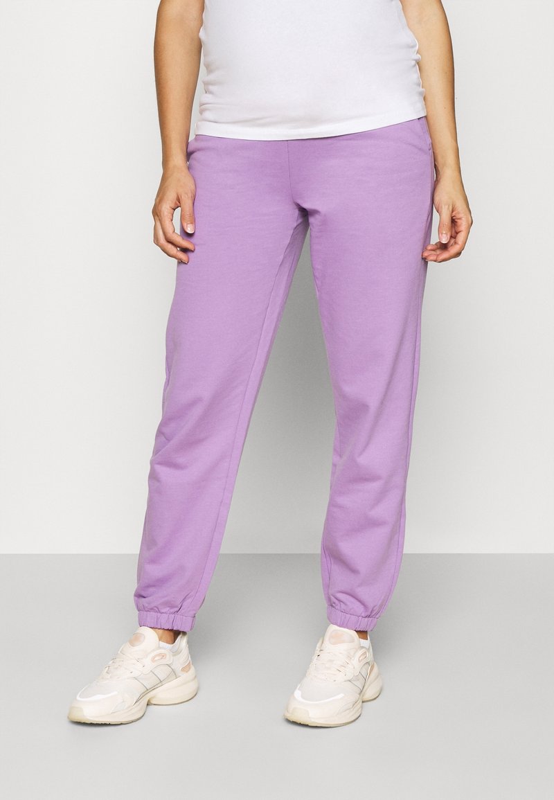 Lilac sweatpants with elastic waistband and cuffs, made of soft fabric. Paired with light-colored athletic shoes. Simple, relaxed fit design.