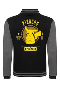 Sort og grå varsity-jakke med et gult Pikachu-grafik, tekst, striber på ærmerne og emblem detaljer.
