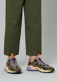 Sneaker multicolori con una combinazione di verde oliva, nero e accenti viola. Presentano una tomaia in tessuto testurizzato, una suola spessa e lacci a contrasto.
