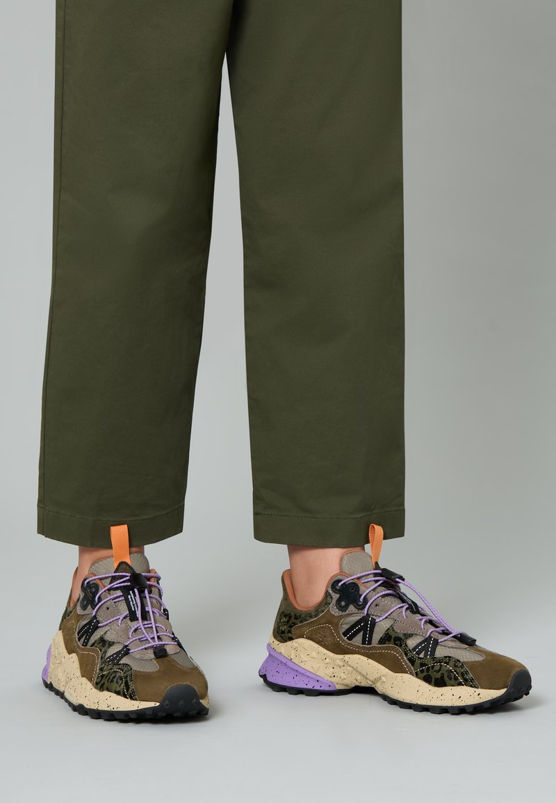 Sneaker multicolori con una combinazione di verde oliva, nero e accenti viola. Presentano una tomaia in tessuto testurizzato, una suola spessa e lacci a contrasto.