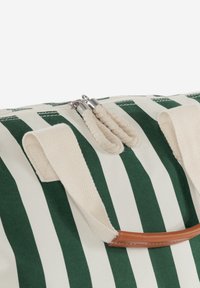 Borsa in tela a strisce verde e crema, con chiusura a zip, tasselli intrecciati e un accento in pelle marrone sul manico.