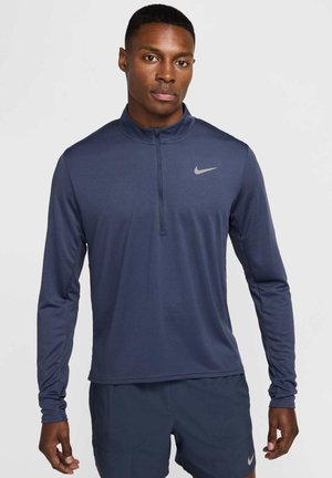Navy quarter-zip long-sleeve athletic top made from moisture-wicking fabric; features subtle Nike logo on chest; smooth texture.