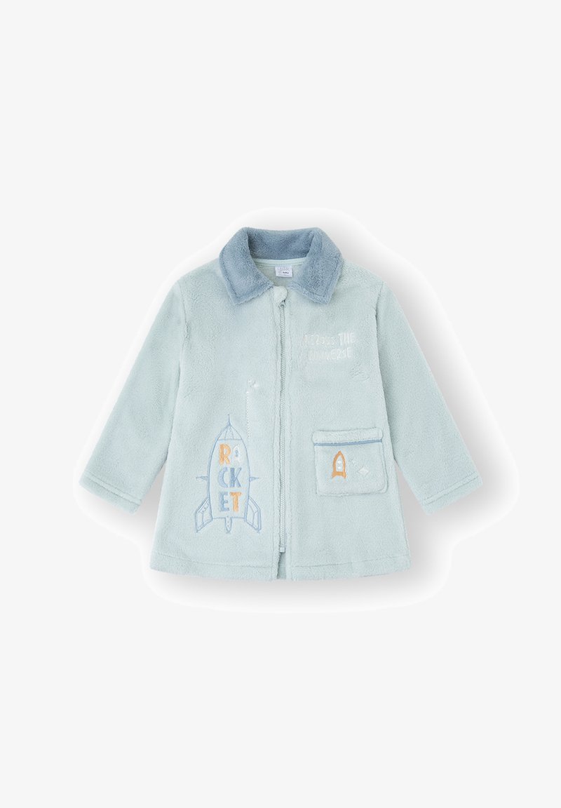 Chaqueta de vellón azul claro con cuello. Presenta un gráfico bordado de un cohete y un bolsillo con un ribete azul. Textura suave, cierre frontal con cremallera.