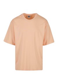 Pfirsichfarbene Baumwoll-T-Shirt mit Rundhalsausschnitt und kurzen Ärmeln. Hat eine lockere Passform und eine glatte, weiche Textur.