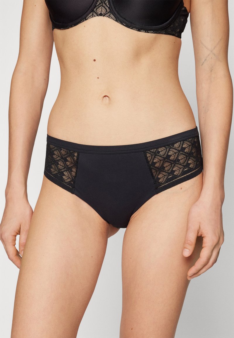 Zwarte lingerie met een gladde stof, kanten zijpanelen met een geometrisch patroon en een klassieke slipstijl.