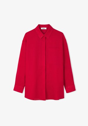 Camicia di lino di un vivace rosso con colletto classico, chiusura anteriore con bottoni, maniche lunghe e una tasca sul petto, con un logo ricamato discreto.