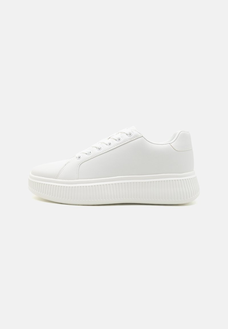 White sneakers with a smooth, synthetic upper, round toe, and streamlined design. They feature a thick, ridged sole for added height.